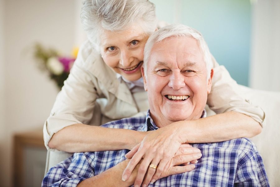 Portrait of senior woman embracing man in living room